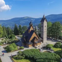 Drewniany kościółek i wieża na tle gór. Czy to Karpacz czy Szklarska Poręba?