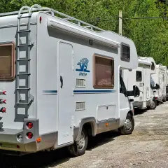 Une file de camping-cars blancs garés dans un paysage verdoyant, prêts pour une aventure à Marseille.