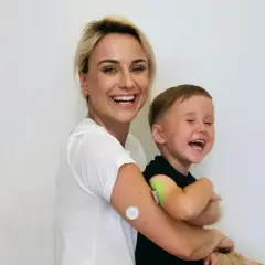 Kobieta z blond włosami i mały chłopiec śmieją się na białym tle.