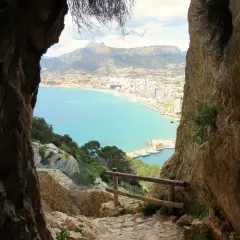 Camino rocoso para subir al Peñón de Ifach, con vistas al mar turquesa y la ciudad.