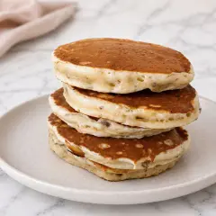 Pile de pancakes banane moelleux, dorés et aérés, servis sur une assiette claire.