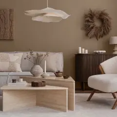Przytulny salon w stylu naturalnym. Miękka sofa, puszysty fotel i kamienne stoliki tworzą oazę spokoju.