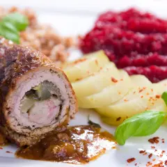 Roladki wołowe z ogórkiem, ziemniakami, kaszą i buraczkami na białym talerzu.