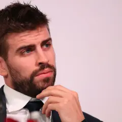 Gerard Piqué w garniturze, z ręką na brodzie, patrzy w bok.