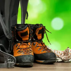 Pomarańczowe buty trekkingowe, plecak i lina. Zadbaj o nie, używając impregnatu do butów z membraną, by były gotowe na każdą wyprawę.