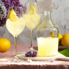 Erfrischender Limoncello Spritz mit Zitronenscheiben, Eis und Flieder.