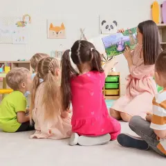 Nauczycielka czyta dzieciom bajkę. Zastanawiasz się, ile kosztuje żłobek miesięcznie? Dzieci słuchają uważnie.
