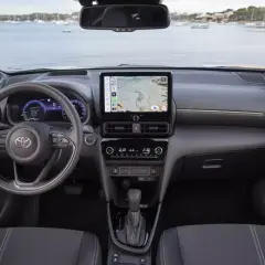 Nowoczesne **toyota yaris cross wnetrze** z ekranem nawigacji i cyfrowymi zegarami. Widok na kierownicę i konsolę środkową.