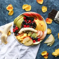 Patera z owocami na wesele: soczyste maliny, borówki, jeżyny, jabłka, gruszki, kiwi, mango, pomarańcze i banan.