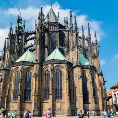 Imponente catedral gótica con sus torres y arcos detallados, bajo un cielo azul con nubes.