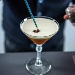 Barista dodaje ziarna kawy do drinka z pianką, przypominającego Espresso Martini. To właśnie Kahlúa nadaje mu ten wyjątkowy, kawowy smak.