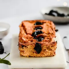 Domowy pasztet z resztek mięsa pieczonego, ozdobiony śliwkami, na desce z nożem i miseczką sosu.