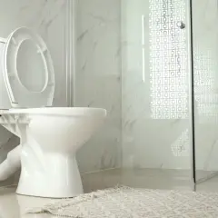 A modern bathroom with a white toilet, open lid, and a copper toilet paper holder. The toilet is not flushing, causing a minor inconvenience.