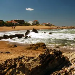 Plaża z domkami w tle, falujące morze i skały. Tak wygląda wybrzeże, gdzie leży Urugwaj.