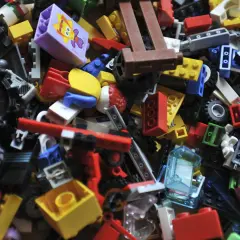 Bunte LEGO Steine sortieren: Ein Haufen verschiedener Bausteine, Räder und Figuren wartet darauf, zu neuen Welten zusammengefügt zu werden.