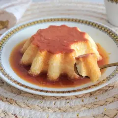 Un delicioso flan casero con caramelo dorado, servido en un plato decorado. Una cucharada revela su textura suave y cremosa.