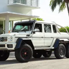 Potężny biały Mercedes G-Class 6x6 z masywnymi oponami i sześcioma kołami, gotowy na każdą przygodę.