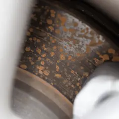 Närbild på en bilbromsskiva med tydlig rost. Fläckar av rost täcker den annars grå metallen.