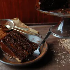 Wilgotny tort czekoladowy z kremem nutella, posypany kakao, czeka na widelca. Obok kawałek czekolady.