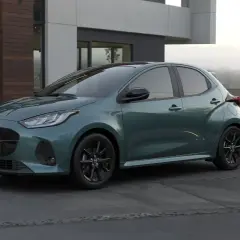 Elegancka, zielona Mazda 2 Hybrid stoi przed nowoczesnym domem.