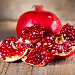 Saftige Granatapfelkerne auf Holz. Die Frucht, woher kommt der Granatapfel, stammt ursprünglich aus Persien und dem Nahen Osten.
