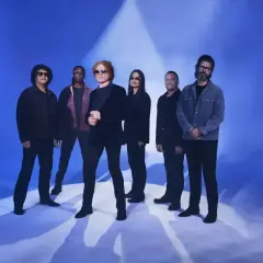 Zespół Simply Red na niebieskim tle, gotowy do koncertu.