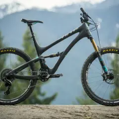 A black Yeti SB5 Turq mountain bike with teal accents sits on a rock, ready for adventure in the mountains.