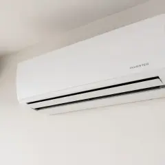 Unidad de aire acondicionado blanca montada en la pared, con la etiqueta "INVERTER" visible.