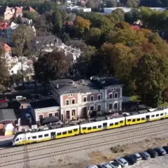 Nowoczesny szynobus pokonuje trasę Wrocław - Trzebnica, mijając malowniczą stację i jesienne drzewa.