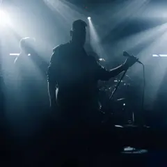 Zespół na scenie, wokalista z mikrofonem, saksofonista. Czy bilety imienne na koncert sprawdzają?