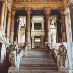 Monumentalne schody z rzeźbami i kolumnami w holu sądu.
