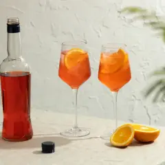 Aperol Spritz przepis: butelka Aperolu, dwa drinki z pomarańczą i lodem, połówki pomarańczy. Idealne na lato.