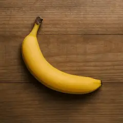 Eine einzelne, reife Banane liegt auf einem Holztisch. Sie ist gelb und leicht gekrümmt. Die Frage "wie viel Protein hat eine Banane" wird hier visuell gestellt.