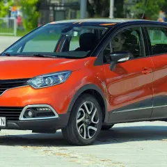 Pomarańczowy Renault Captur 2015 z czarnym dachem i felgami stoi na placu.