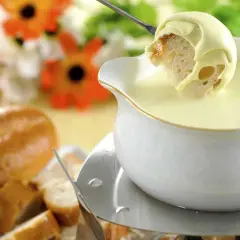 Un pezzo di pane intinto in una fonduta cremosa, un modo delizioso per sciogliere il formaggio.