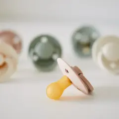 Kilka smoczków Bibs w pastelowych kolorach, jeden z nich z żółtym sutkiem, idealny dla delikatnego podniebienia maluszka.