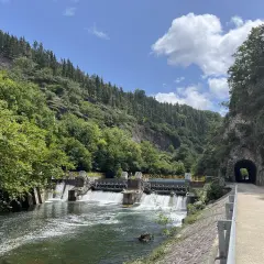 Un camino junto al río Bidasoa, con una presa y un túnel en la montaña.
