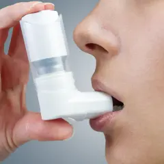 Kobieta używa inhalatora, który może zawierać najnowsze leki na astmę oskrzelową.