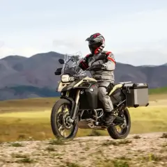 Motocyklista w pełnym rynsztunku przemierza górskie tereny na motocyklu BMW 800 GS.