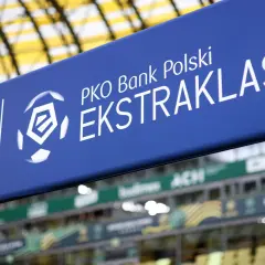 Niebieski baner z logo PKO Bank Polski Ekstraklasa na tle stadionu.