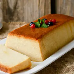 Un delicioso pudin de pan, con una capa dorada y decorado con frutos rojos y menta.