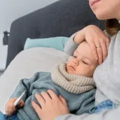 Matka sprawdza temperaturę chorego dziecka, które ma gorączkę.