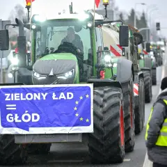 Traktor z banerem "Zielony Ład = Głód" i flagą UE, w tle protestujący rolnicy.