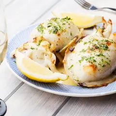 Delicioso sepia a la plancha, servido con gajos de limón y perejil picado, acompañado de una copa de vino blanco.
