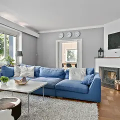 Blau passt toll zu seidengrau, wie dieses Wohnzimmer mit blauem Sofa, Kamin und Kuhfellhockern zeigt.