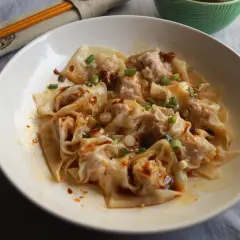 Pyszne pierożki wonton polane pikantnym sosem, posypane szczypiorkiem i sezamem. Ciasto do wontonów jest cienkie i delikatne.