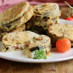 Deliziosi cordon bleu di melanzane impanati e fritti, con un ripieno filante di formaggio e prosciutto, guarniti con pomodorini freschi.