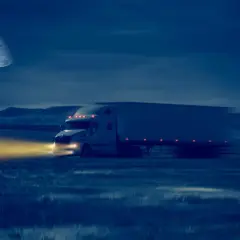 Ciężarówka przemierza pustkowie w **godziny nocne**, kierowca w drodze. Księżyc oświetla trasę.