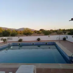 Piscina con vistas a montañas y vegetación bajo un cielo despejado.