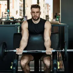 Mann trainiert Bizeps mit Langhantel im Fitnessstudio. Calisthenics-Liebhaber baut Muskeln auf.